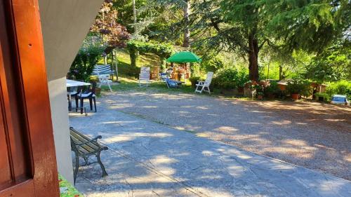 a patio with chairs and tables and a green umbrella at Appartamento Il GIRASOLE in Scarperia
