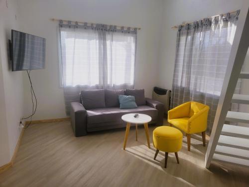 sala de estar con sofá y silla amarilla en Casita Catalejo Travel, en Puerto Madryn