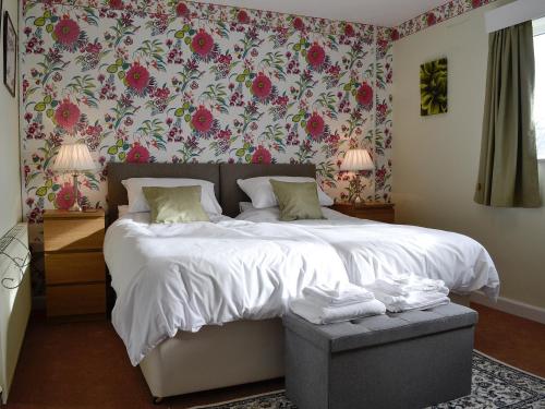 a bedroom with a large bed with a floral wallpaper at Merryview Bungalow in Orcop