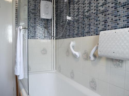 a shower with a glass door in a bathroom at Merryview Bungalow in Orcop