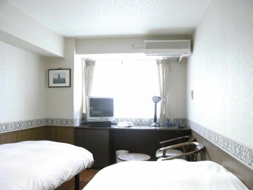 a room with two beds and a tv and a window at Sunplaza Rinkai in Osaka