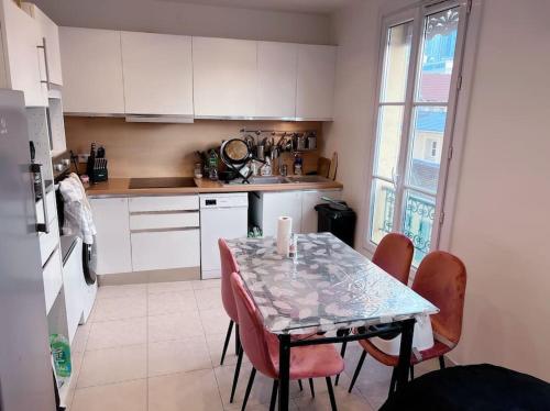 eine Küche mit einem Tisch und Stühlen sowie einem Tisch und einem Fenster in der Unterkunft Elegance et Confort - Votre Havre Luxueux pour les Jeux Olympiques à Paris in Puteaux