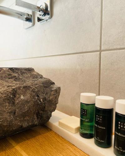 a group of three bottles on a shelf next to a rock at Private Spa Lodge Odenwald in Lindenfels
