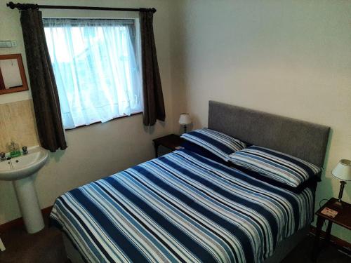 1 dormitorio con cama, lavabo y ventana en Mirandas Guest House, en Berwick-Upon-Tweed