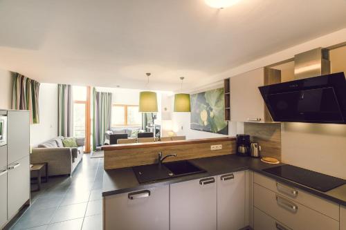 a kitchen with a sink and a living room at Lipno Lake Resort in Lipno nad Vltavou