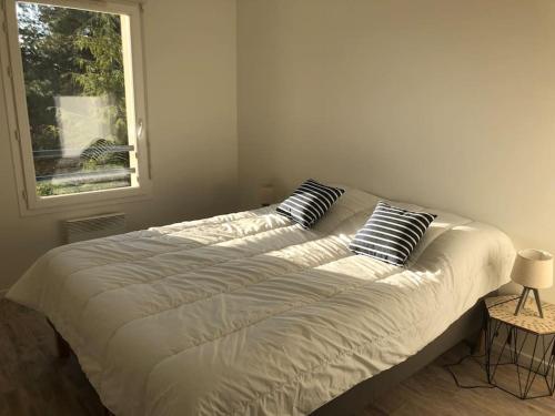 un lit avec deux oreillers dessus dans une chambre dans l'établissement Appartement à Royan avec accès piscine, à Royan