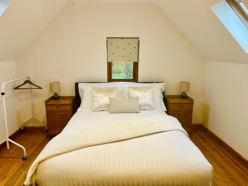 um quarto com uma grande cama branca com duas mesas de cabeceira em The Annexe at Yew Tree House em Canterbury