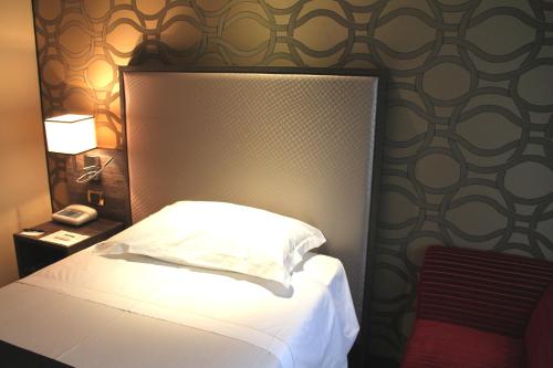 a bedroom with a bed and a nightstand with a phone at Hotel Mozart in Milan