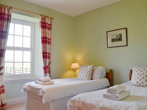 two beds in a room with a window at Osprey Cottage - Uzq in Kirkton of Airlie