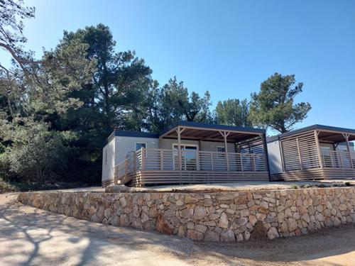 ein Haus mit einer Steinwand und einer Steinwand in der Unterkunft Mobilne kućice Lavanda in Osor