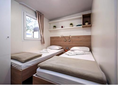2 Betten in einem kleinen Zimmer mit Fenster in der Unterkunft Mobilne kućice Lavanda in Osor