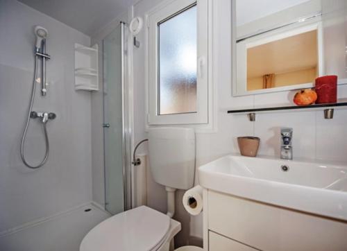 a white bathroom with a toilet and a sink at Mobilne kućice Lavanda in Osor