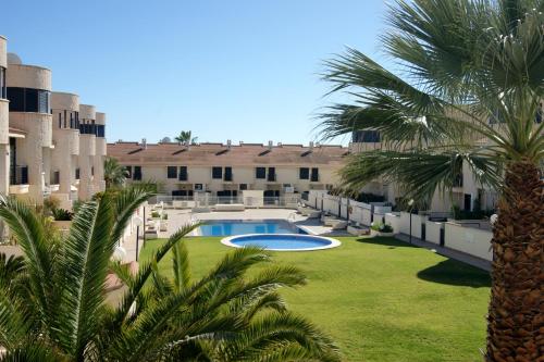 a courtyard with a swimming pool and palm trees at REGIA BAHIA - Cabo Roig - SEA VIEW in Playas de Orihuela