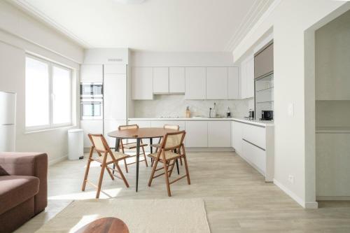 cocina y comedor con mesa y sillas en Bel appartement épuré 2 chambres Brugmann, en Bruselas