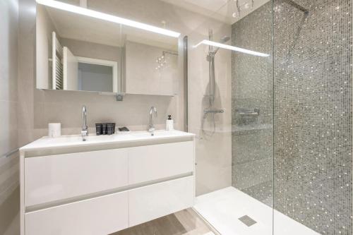 y baño blanco con lavabo y ducha. en Bel appartement épuré 2 chambres Brugmann, en Bruselas