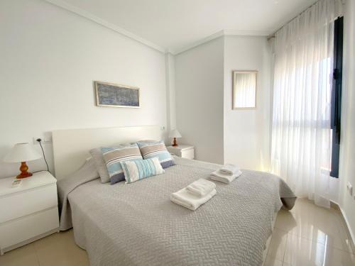 プレヤス・デ・オリフエラにあるREGIA BAHIA - Cabo Roig - SEA VIEWの白いベッドルーム(タオル付きのベッド付)