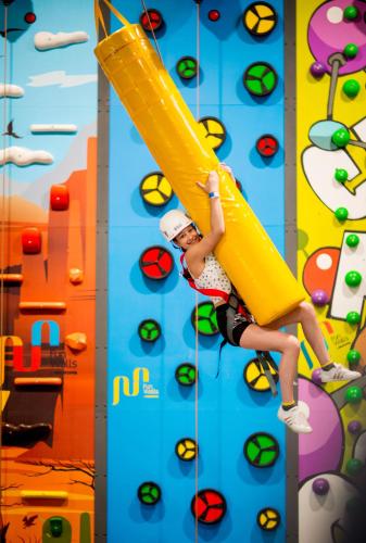 a woman is climbing a climbing wall at Kolping Family Resort in Hévíz