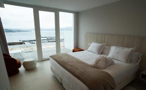 a bedroom with a white bed with a large window at Otantus Hotel in Muros