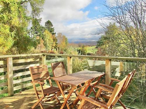 a wooden table and two chairs on a deck at The Byre - by Where Stags Roar in Newtonmore