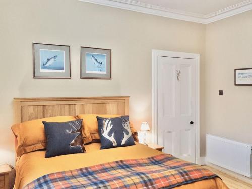 a bedroom with a bed with three pictures on the wall at Caman House Apt 2 - by Where Stags Roar in Newtonmore