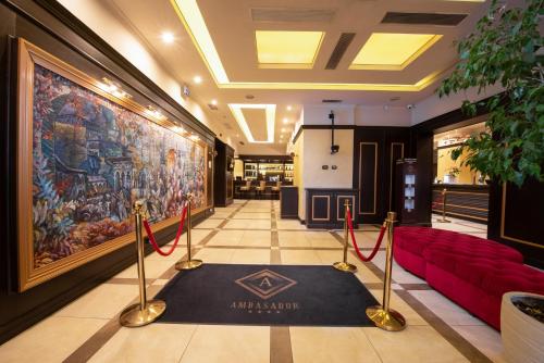 ブカレストにあるホテル アンバサダーの赤いソファと大きな絵画が飾られたロビー