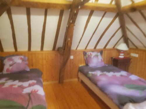 een slaapkamer met 2 bedden in een kamer met houten vloeren bij HAMPTON COTTAGE in Aubry-le-Panthou