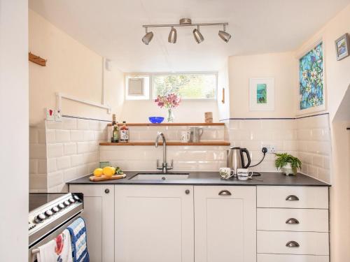 a kitchen with white cabinets and a sink at Trevivian House in Boscastle