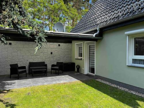 a patio with chairs and a table next to a house at -Haus am Wäldchen- in Zehdenick