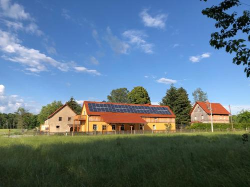 ein Haus mit Sonnenkollektoren auf einem Feld in der Unterkunft Ferienhof Olbasee in Kleinsaubernitz