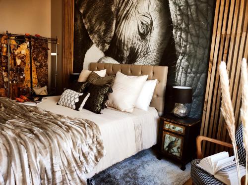 - une chambre avec un lit orné d'une peinture d'éléphant sur le mur dans l'établissement Appartements design - Uniques - Centre, à Bagnères-de-Bigorre