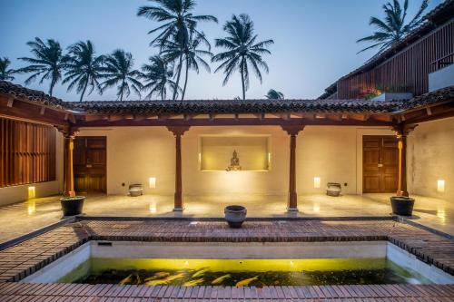 a courtyard of a house with a pond and palm trees at Villa Thamburu, Bentota in Bentota