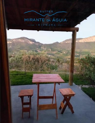 a picnic table and two stools on a porch at Suítes Mirante da Águia in Ibicoara