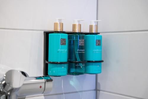 a group of four blue bottles on a bathroom sink at Birkebeineren Hotel & Apartments in Lillehammer