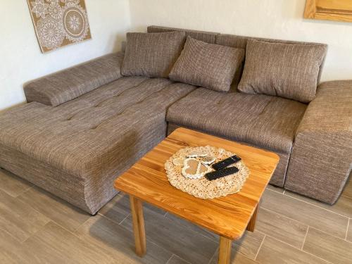 a living room with a brown couch and a wooden table at Tiszavirág Vendégház in Tiszacsege