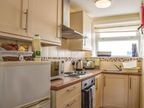 a kitchen with white cabinets and a stove top oven at Kite Cottage in Llandeilo