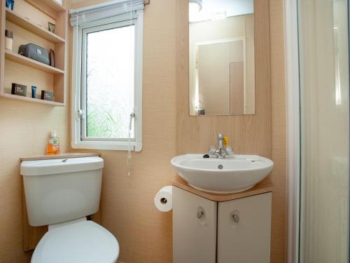 a bathroom with a toilet and a sink and a window at Retro Retreat in Goodrington