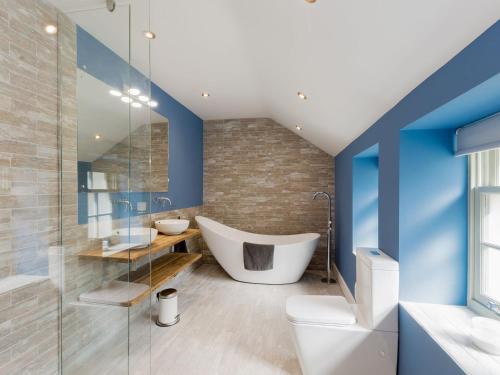 a bathroom with blue walls and a tub and a toilet at Ivy Cottage in Beck Hole