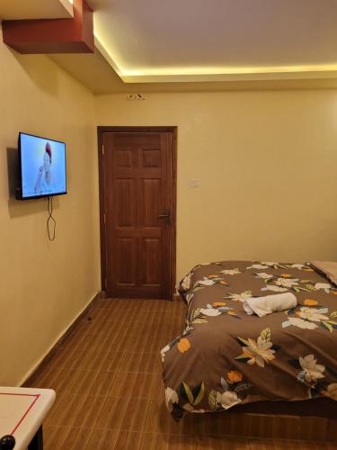 a bedroom with a bed and a flat screen tv at STERLEON HOTEL RIVERSIDE in Nairobi