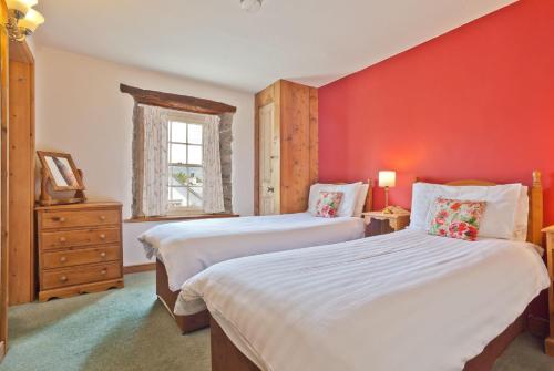 1 dormitorio con 2 camas y pared roja en The Old Post Cottage, Coniston, en Coniston