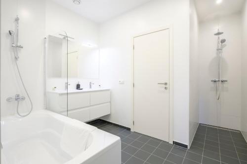 een witte badkamer met een bad en een wastafel bij Magnifique Appartement 3 chambres vue Théâtre de la Monnaie in Brussel