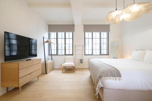 een slaapkamer met een bed en een flatscreen-tv bij Magnifique Appartement 3 chambres vue Théâtre de la Monnaie in Brussel