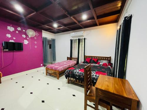 1 dormitorio con 2 camas, mesa y TV en Mundro Garden Homestay, en Munroe Island