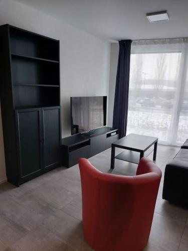 a living room with a red chair and a table at Appartement 2p1/2 pour couple ou famille in Romont