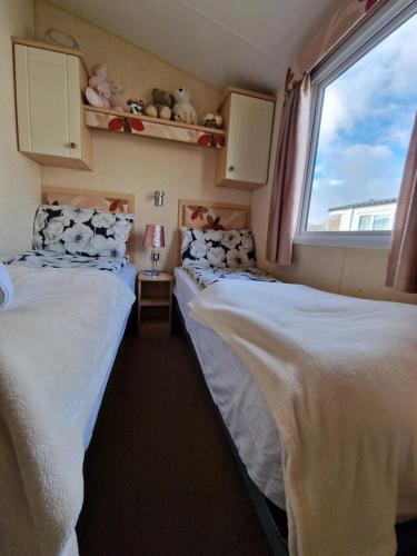 two beds in a small room with a window at Caravan in the Cotswolds in Cirencester