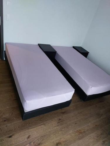 dwa białe łóżka siedzące na drewnianej podłodze w obiekcie Appartement 2p1/2 pour couple ou famille w mieście Romont