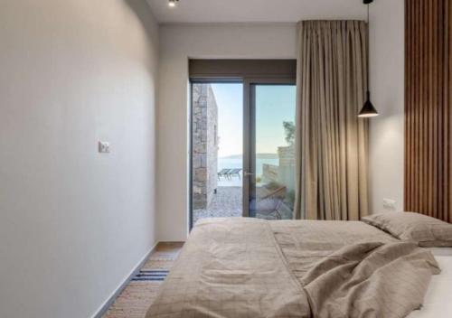 a bedroom with a bed and a large window at Villa Alliopi ein Blick für die Sinne in Kranidi
