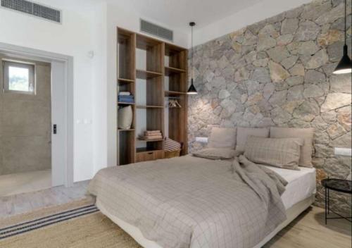 a bedroom with a large bed and a stone wall at Villa Alliopi ein Blick für die Sinne in Kranidi