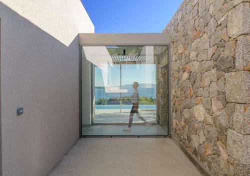 a person walking through a glass door of a building at Villa Alliopi ein Blick für die Sinne in Kranidi