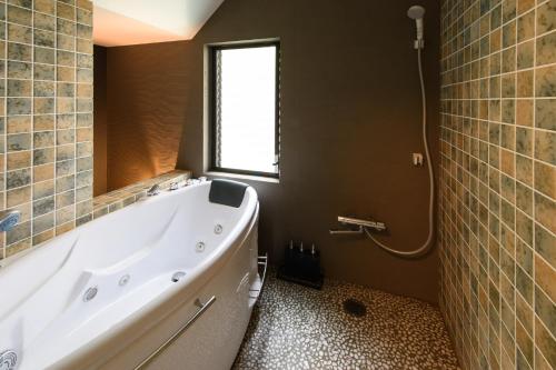 a bathroom with a large tub and a window at UFU Kanazawa in Kanazawa