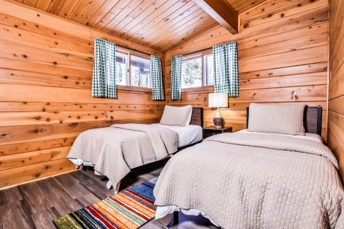 Dos camas en una cabaña de troncos con paredes y ventanas de madera. en Behnkes Bungalow, en Manitowish Waters